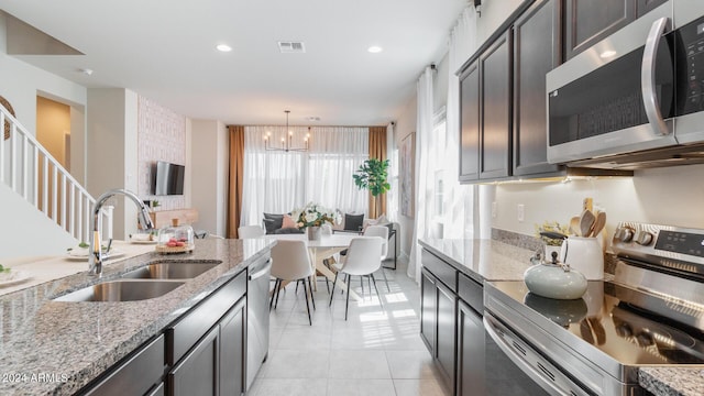 kitchen featuring visible vents, light tile patterned floors, light stone counters, appliances with stainless steel finishes, and a sink