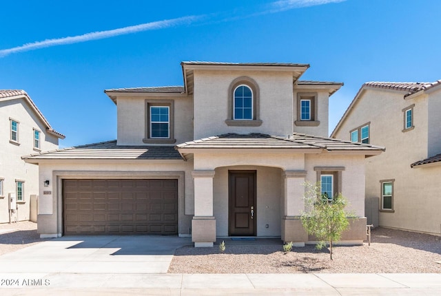 view of front facade with stucco siding, an attached garage, a tile roof, and driveway