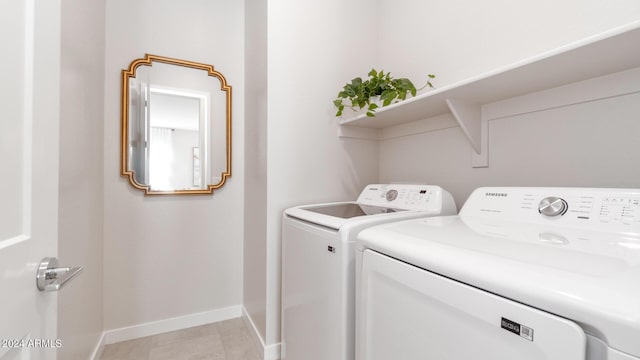 clothes washing area with light tile patterned floors, laundry area, washer and dryer, and baseboards