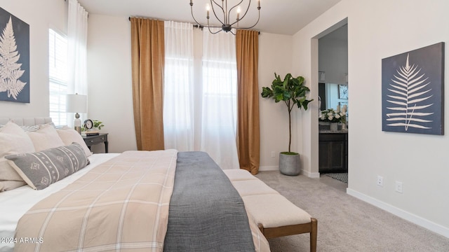 carpeted bedroom featuring ensuite bath, an inviting chandelier, and baseboards