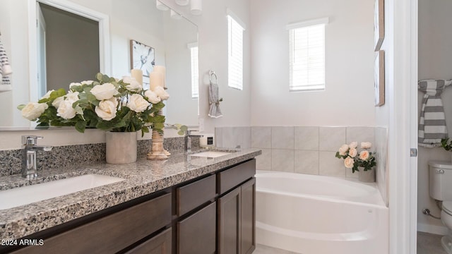 bathroom featuring double vanity, toilet, a garden tub, and a sink