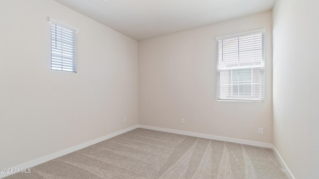 unfurnished room featuring light colored carpet and baseboards