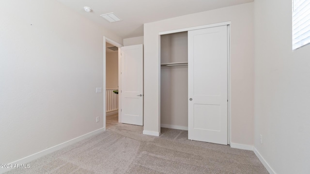 unfurnished bedroom with carpet, baseboards, and a closet