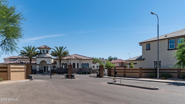 view of road with curbs, street lights, a gated entry, and sidewalks