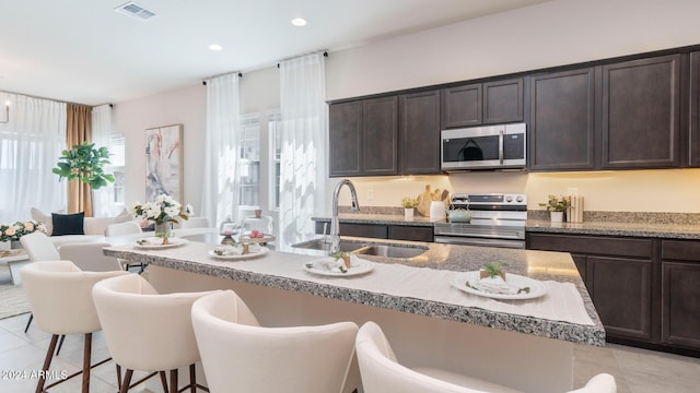 kitchen featuring visible vents, a breakfast bar, light tile patterned flooring, a sink, and appliances with stainless steel finishes