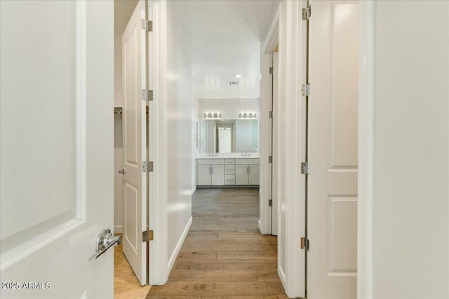 corridor with sink and light wood-type flooring