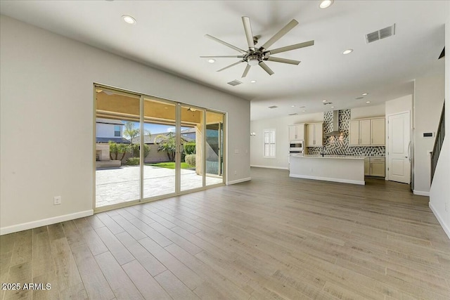 unfurnished living room featuring ceiling fan and light hardwood / wood-style flooring