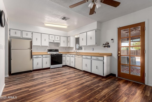 kitchen with white appliances, visible vents, dark wood finished floors, a sink, and under cabinet range hood