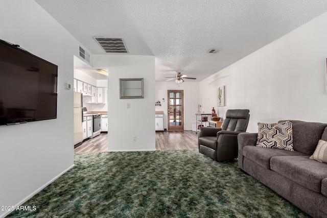 carpeted living room featuring a textured ceiling, visible vents, and ceiling fan