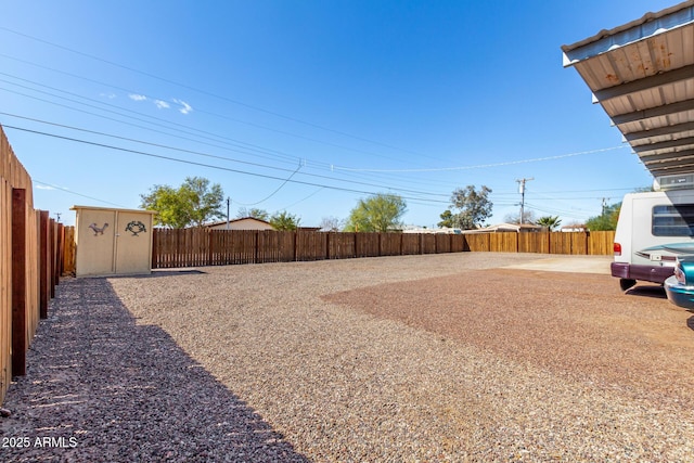 view of yard featuring a storage unit, a fenced backyard, and an outdoor structure