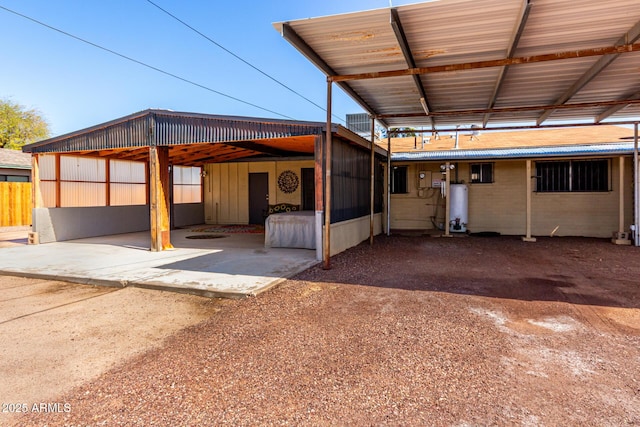 exterior space with a carport, fence, and water heater