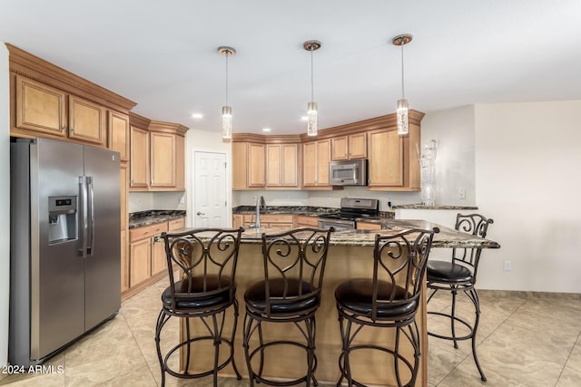 kitchen featuring appliances with stainless steel finishes, a breakfast bar, pendant lighting, and dark stone counters