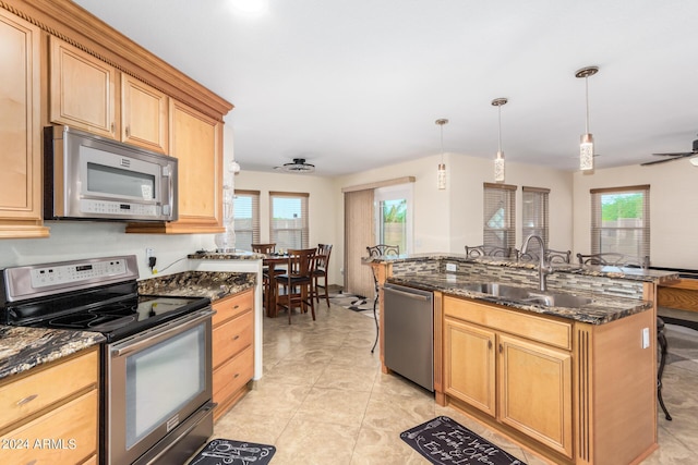 kitchen with sink, a breakfast bar area, dark stone countertops, hanging light fixtures, and stainless steel appliances