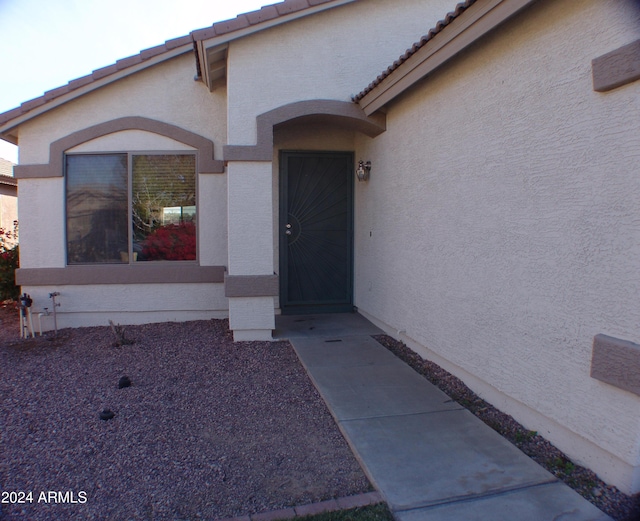 doorway to property featuring a tile roof and stucco siding