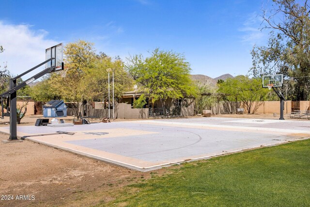 view of sport court featuring a mountain view and a yard