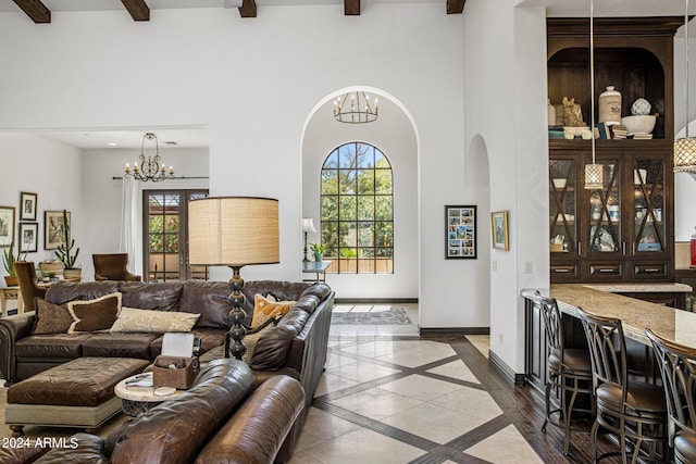 living room with beamed ceiling, a notable chandelier, a towering ceiling, and plenty of natural light