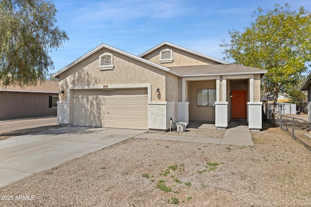 view of front facade with fence, an attached garage, concrete driveway, and stucco siding