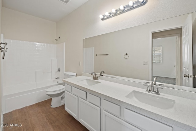 bathroom with a sink, washtub / shower combination, wood finished floors, and toilet
