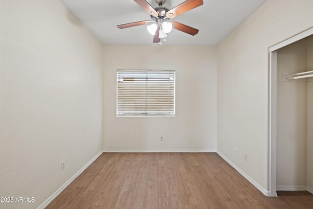 unfurnished bedroom featuring baseboards, a ceiling fan, a closet, and wood finished floors