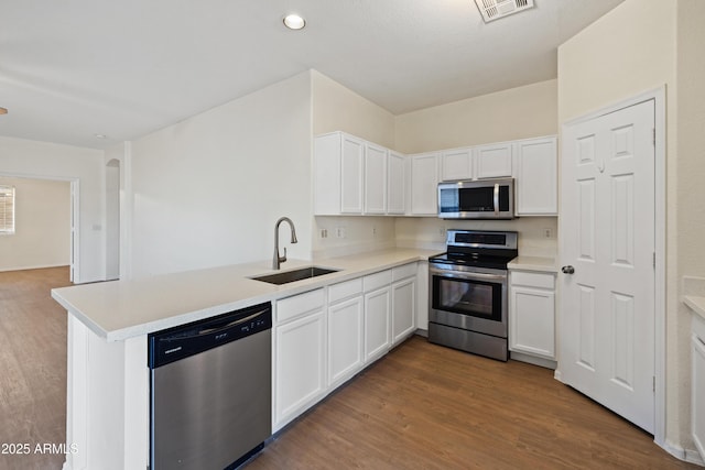 kitchen with white cabinets, a peninsula, appliances with stainless steel finishes, and a sink