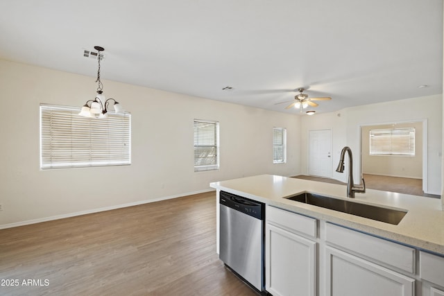 kitchen with stainless steel dishwasher, wood finished floors, white cabinets, a sink, and hanging light fixtures