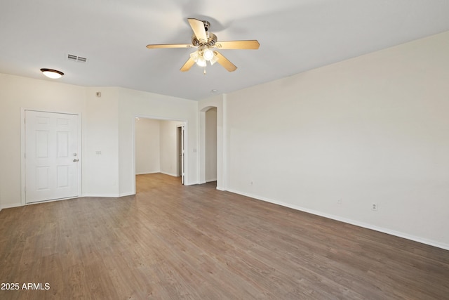 unfurnished room with a ceiling fan, arched walkways, visible vents, and wood finished floors
