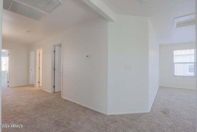 spare room featuring light carpet and beam ceiling