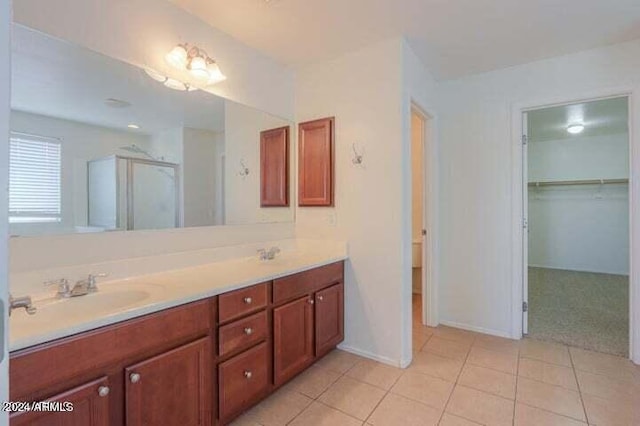 bathroom with a shower with door, vanity, and tile patterned flooring