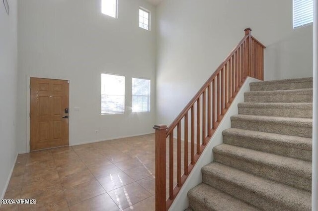 stairway with tile patterned flooring and a high ceiling