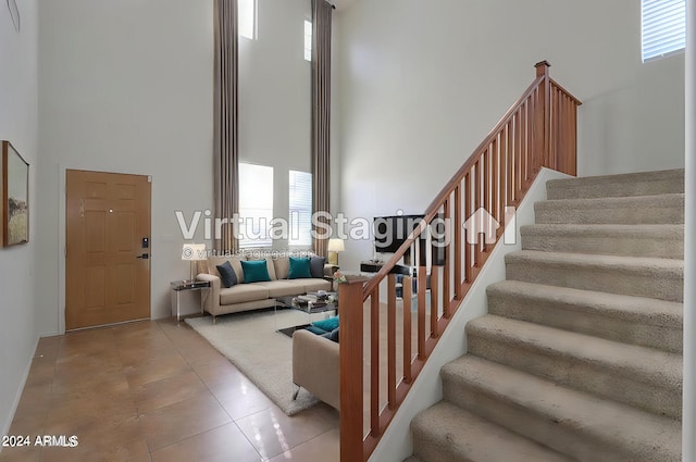 stairway with tile patterned floors and a high ceiling