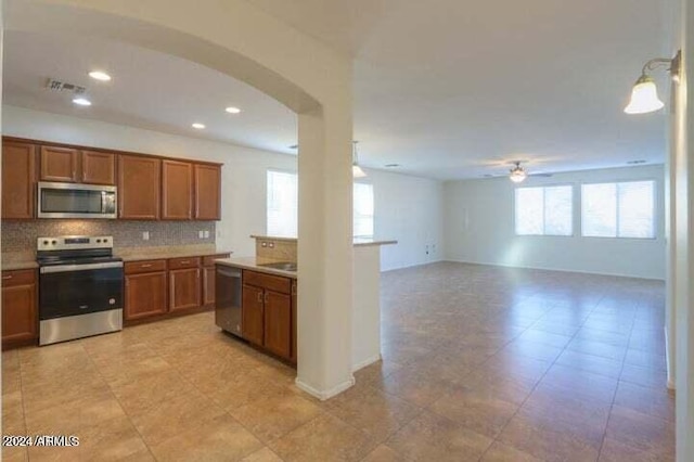 kitchen with stainless steel appliances, a healthy amount of sunlight, backsplash, and ceiling fan