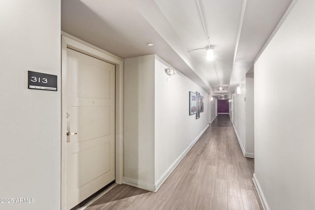 hallway with light wood finished floors and baseboards