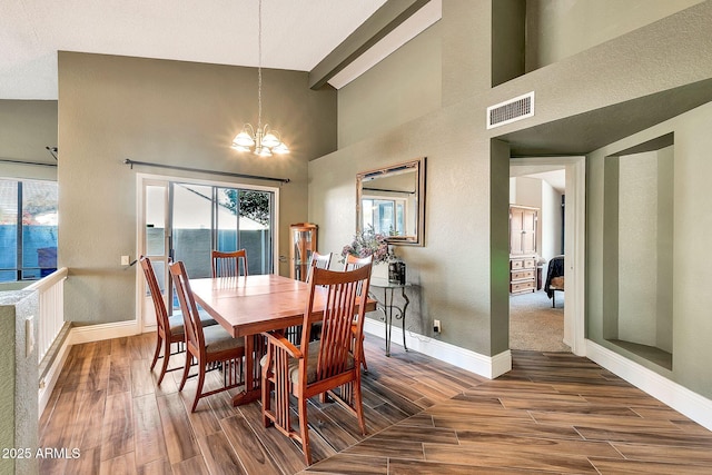 dining area with hardwood / wood-style flooring, a water view, a chandelier, and a towering ceiling