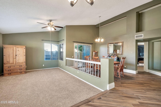 empty room with ceiling fan with notable chandelier, high vaulted ceiling, wood-type flooring, and a textured ceiling