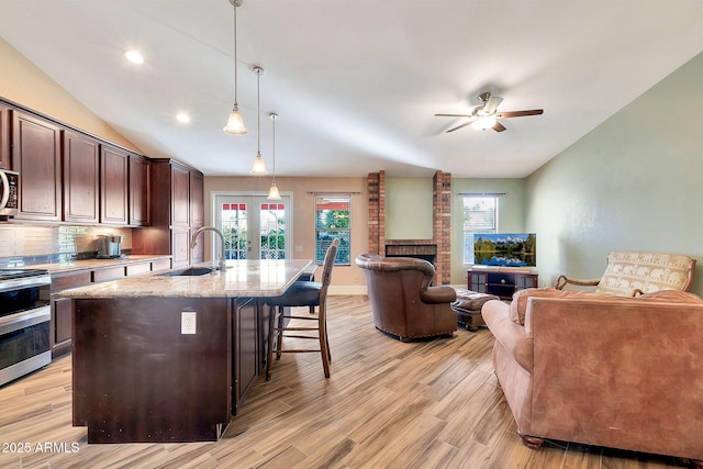 kitchen featuring a center island with sink, stainless steel appliances, pendant lighting, a breakfast bar, and sink