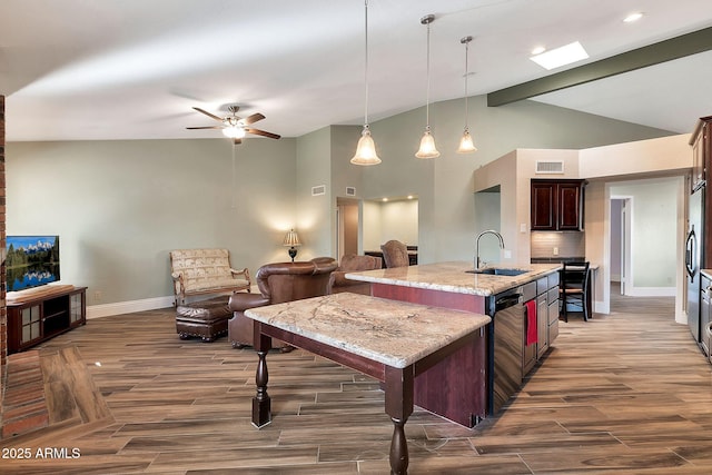 kitchen with a center island with sink, sink, backsplash, light stone counters, and pendant lighting