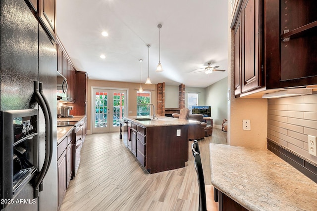 kitchen featuring sink, decorative light fixtures, stainless steel appliances, a kitchen island with sink, and tasteful backsplash