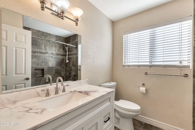 bathroom with tiled shower, vanity, and toilet