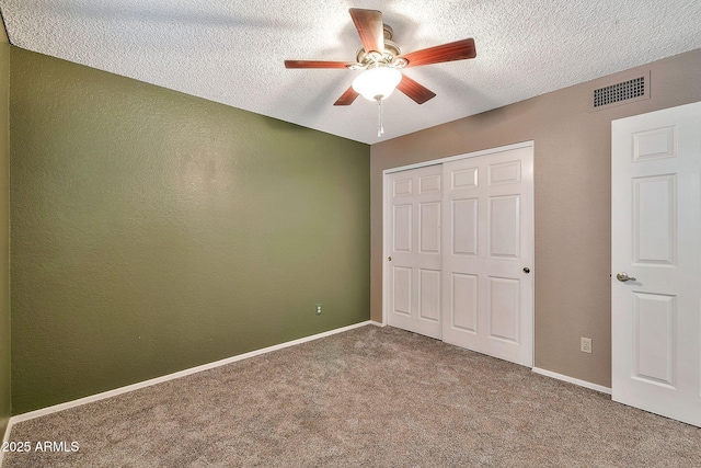 unfurnished bedroom featuring a closet, ceiling fan, carpet flooring, and a textured ceiling