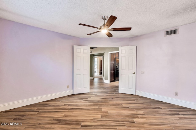 empty room featuring hardwood / wood-style flooring, ceiling fan, and a textured ceiling