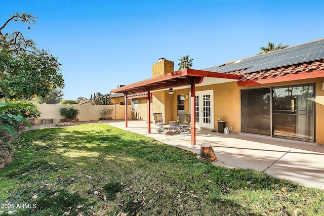 rear view of house featuring a yard, a patio, and solar panels