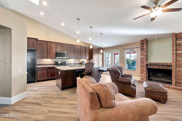 kitchen featuring a kitchen island with sink, pendant lighting, light hardwood / wood-style flooring, dark brown cabinets, and black fridge