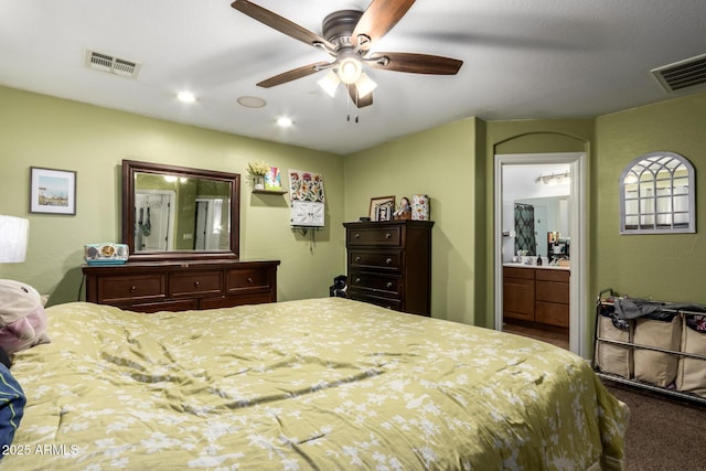 bedroom with ceiling fan, ensuite bath, and carpet flooring