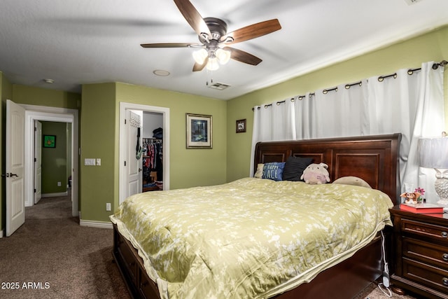 bedroom with a spacious closet, dark carpet, a closet, and ceiling fan