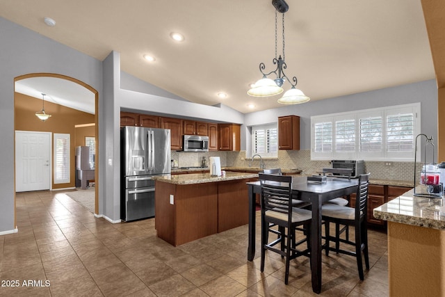 11101 W Wilshire Dr, Avondale, AZ 85392 - kitchen with appliances with stainless steel finishes, vaulted ceiling, arched walkways, backsplash, and a kitchen island