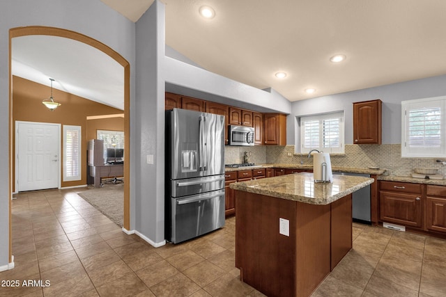 11101 W Wilshire Dr, Avondale, AZ 85392 - kitchen featuring appliances with stainless steel finishes, vaulted ceiling, backsplash, healthy amount of natural light, and tile patterned flooring