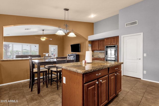 11101 W Wilshire Dr, Avondale, AZ 85392 - kitchen with stainless steel double oven, lofted ceiling, a ceiling fan, arched walkways, and baseboards