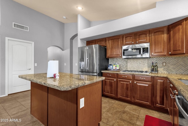 11101 W Wilshire Dr, Avondale, AZ 85392 - kitchen featuring stainless steel appliances, backsplash, arched walkways, light stone countertops, and light tile patterned floors