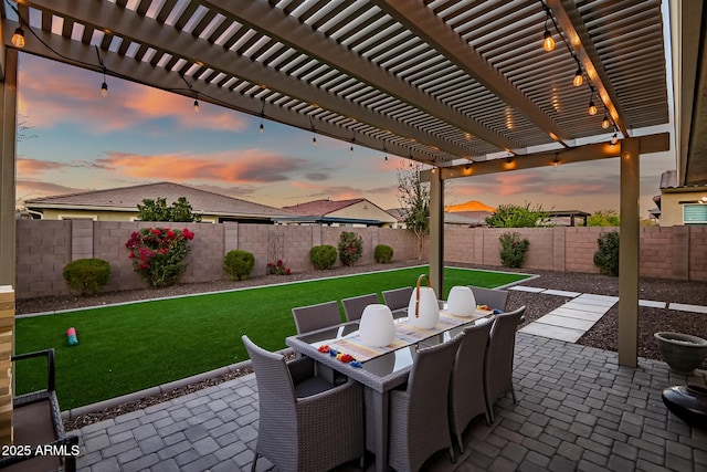 patio terrace at dusk featuring a lawn and a pergola