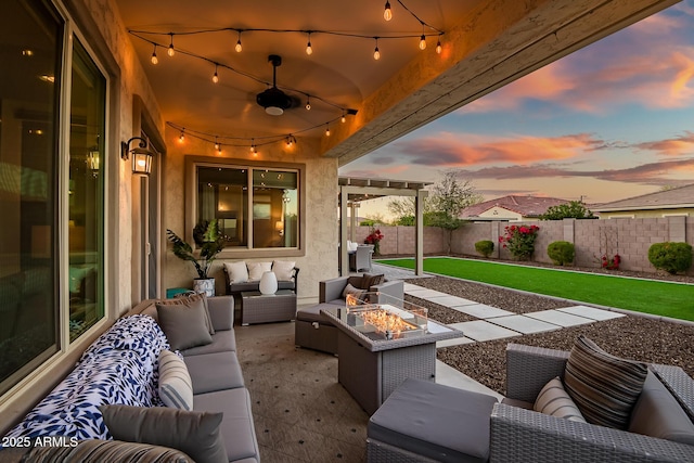 patio terrace at dusk featuring an outdoor living space with a fire pit and a lawn